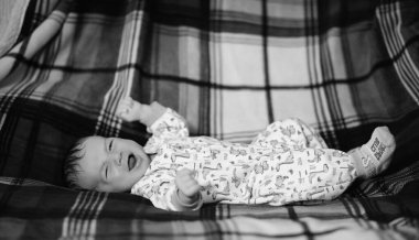 Yeni doğmuş bebek sepet ve ekose üzerinde yatıyor.