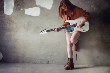 Kızıl saçlı kız bir elektro gitar ile. Rock müzisyen GIR