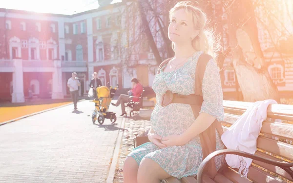 Schwangere Mädchen bei einem Spaziergang im Park. Mädchen mit einem Bauch in der Hand — Stockfoto