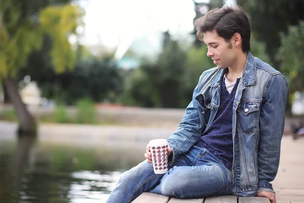 A young man walks in the park at lunch time. A man is on a walk