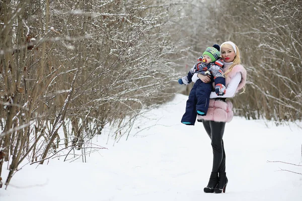 Ung mamma går på en vinterdag med en baby i famnen i th — Stockfoto