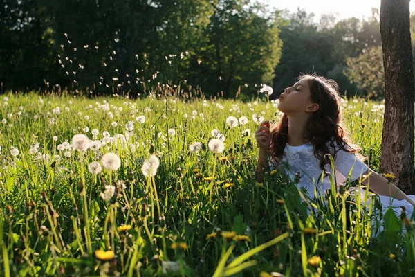 Підліток дме насіння з квітки кульбаби в весняному парку — стокове фото