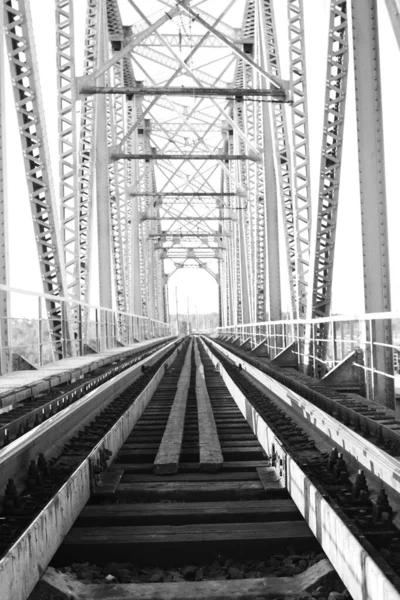 Monochrome photo of the bridge on the railroad tracks and indust — Stock Photo, Image