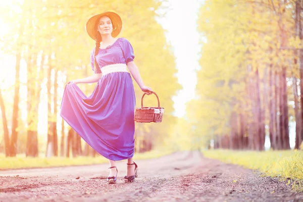 Ung vacker flicka i klänningar på naturen. En tjej i en hatt går — Stockfoto