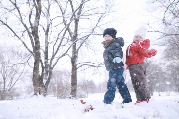 Dzieci chodzą w parku pierwszy śnieg — Zdjęcie stockowe