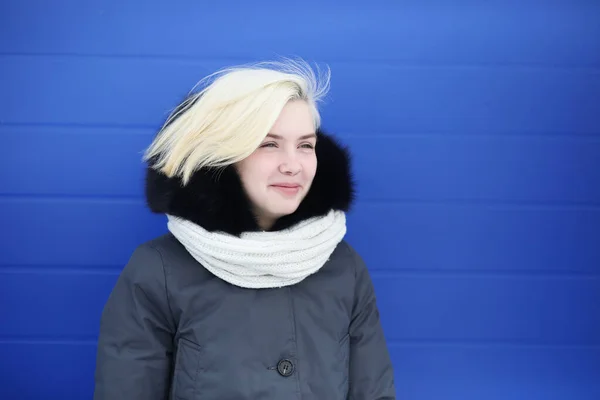 Jovem menina bonita em um passeio no inverno na parede azul — Fotografia de Stock