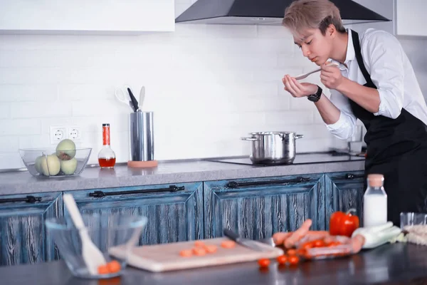 Asian cook in the kitchen prepares food in a cook suit