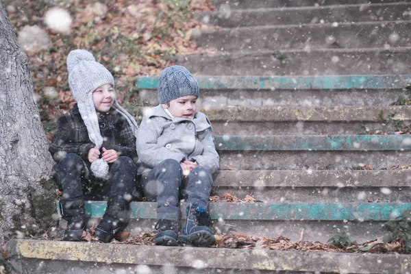 Дети ходят по парку первым снегом — стоковое фото