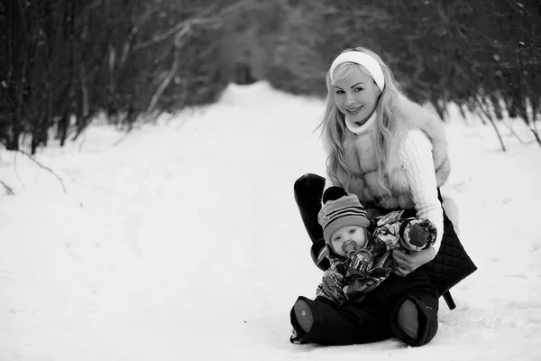 Una joven madre camina en un día de invierno con un bebé en sus brazos — Foto de Stock