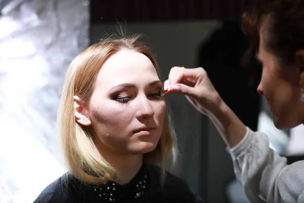 Ung flicka med en make-up artist — Stockfoto