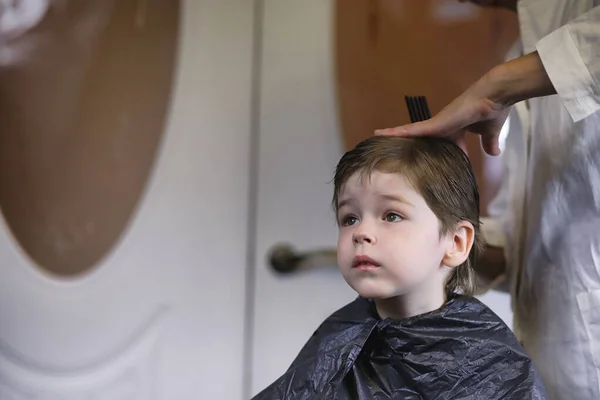 Hairdresser and boy. The boy is doing his hair. Cut hair child i