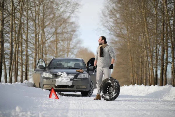 Ein Mann in der Nähe eines kaputten Autos an einem Wintertag — Stockfoto