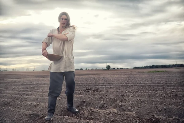 Ein junger Bauer sät das Feld mit Getreide — Stockfoto