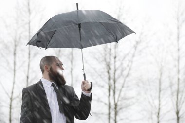 Takım elbiseli kel sakallı bir adam.