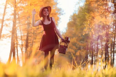 Parkta bir yürüyüş üzerinde şapkalı bir kız. Bir kızla bir sepet yürüyüş