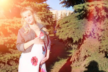 Hamile kız parkta bir yürüyüş. CI karnından kızla