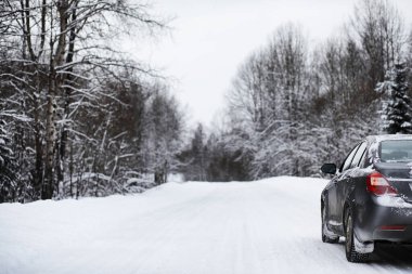 Bir karla kaplı yolda araba duruyor