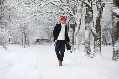 Parkta yürüyen bir adam. Genç adam kışın karla kaplı