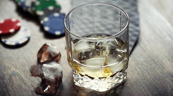 Whisky con ghiaccio e bicchiere. Cubi di ghiaccio su un tavolo di legno un — Foto Stock