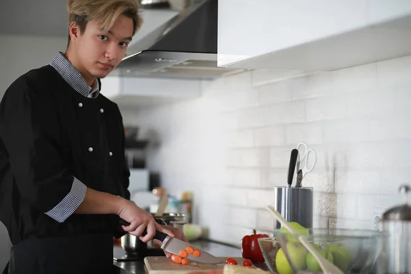 Cocinero asiático en la cocina prepara la comida en un traje de cocinero — Foto de Stock