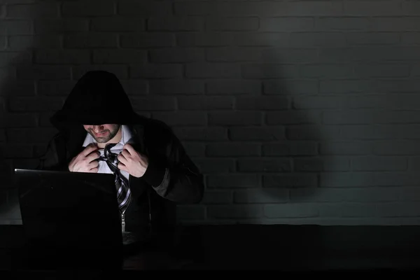 Hacker mit schwarzer Maske und Kapuze am Tisch — Stockfoto