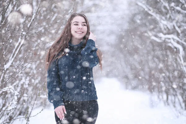 Flicka i en vinterpark i snöfall — Stockfoto