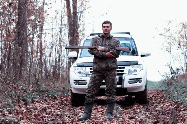 Un hombre en camuflaje y con un rifle de caza en un bosque en una sp —  Fotos de Stock