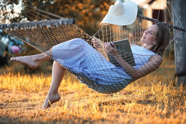 Schönes Mädchen in der Hängematte liest ein Buch — Stockfoto