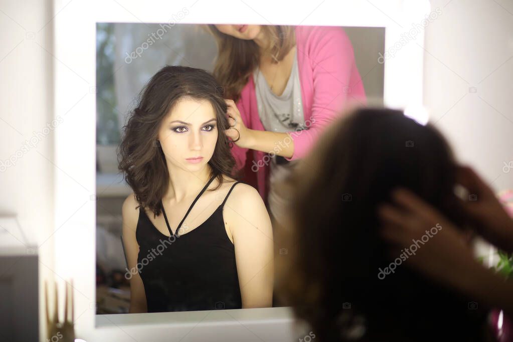 Beautiful girl doing makeup in front of a mirro