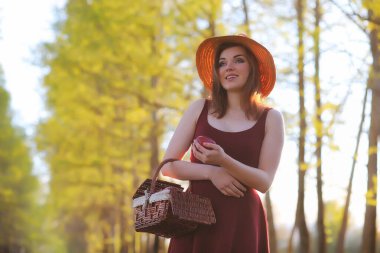 Parkta bir yürüyüş üzerinde şapkalı bir kız. Bir kızla bir sepet yürüyüş