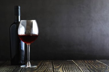 Masada bir bardak kırmızı kuru şarap. Siyah şişe ve bir bardak W