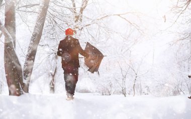Parkta yürüyen bir adam. Genç adam kışın karla kaplı