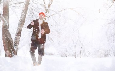 Parkta yürüyen bir adam. Genç adam kışın karla kaplı