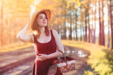 Parkta bir yürüyüş üzerinde şapkalı bir kız. Bir kızla bir sepet yürüyüş