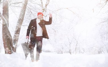 Parkta yürüyen bir adam. Genç adam kışın karla kaplı