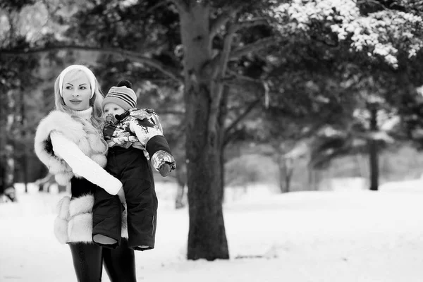 Een jonge moeder loopt op een winterdag met een baby in haar armen — Stockfoto