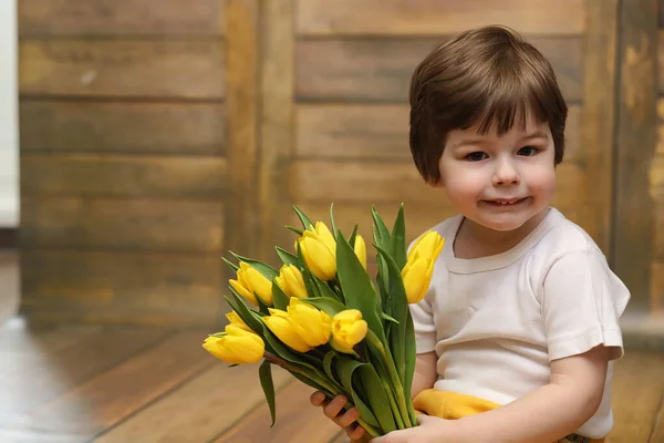 Bir buket Sarı laleler ile küçük bir çocuk. Bir çocuk bir hediye ile — Stok fotoğraf