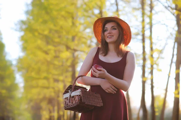 一个戴帽子的女孩在公园里散步。一个带着篮子散步的女孩 — 图库照片