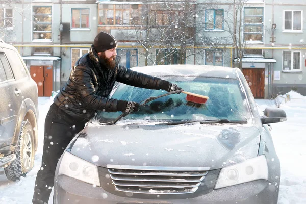 Homem limpa a neve do vidro no carro — Fotografia de Stock