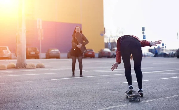 Una giovane hipster sta cavalcando uno skateboard. Ragazze amiche f — Foto Stock