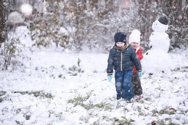 Dzieci chodzą w parku pierwszy śnieg — Zdjęcie stockowe