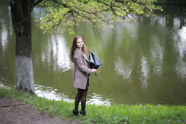 Jeune fille dans un manteau dans un parc de printemps — Photo