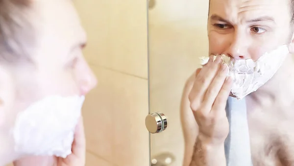 Um homem faz a barba na casa de banho pela manhã — Fotografia de Stock