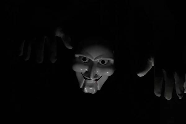 White scary mask on a black background with whites hand. — Stock Photo, Image