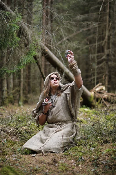 Un hombre en una sotana pasa un ritual en un bosque oscuro — Foto de Stock