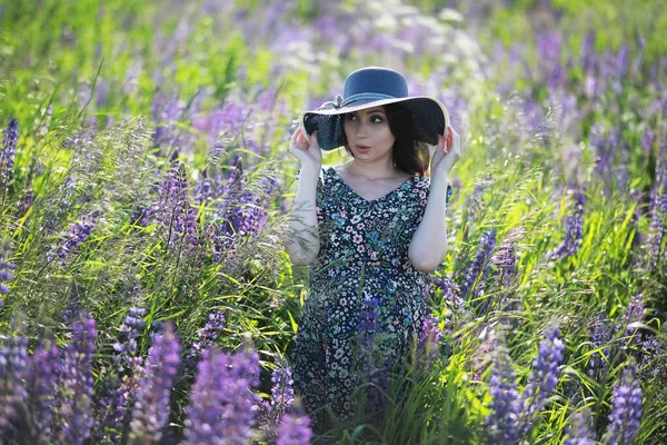 Ciężarna dziewczyna w polu z łubinami — Zdjęcie stockowe