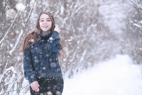 Flicka i en vinterpark i snöfall — Stockfoto