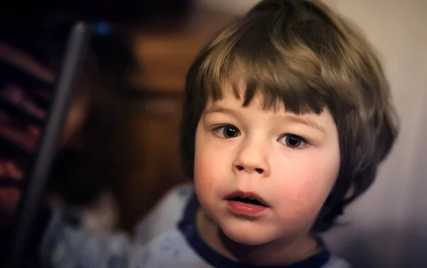 Retrato de un niño de pelo rizado. Un niño envuelto en una alfombra e — Foto de Stock