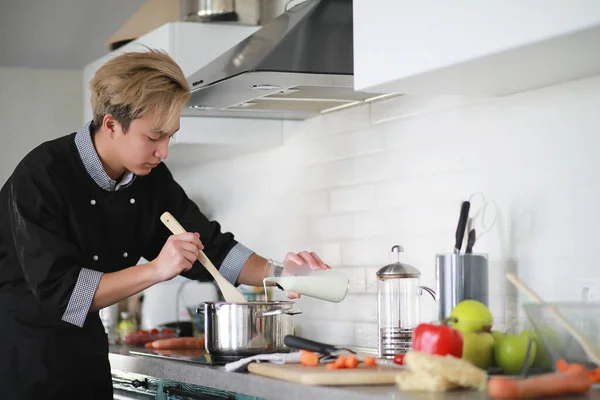 Asian cook in the kitchen prepares food in a cook suit