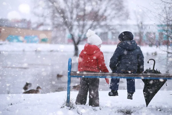 Dzieci chodzą w parku pierwszy śnieg — Zdjęcie stockowe